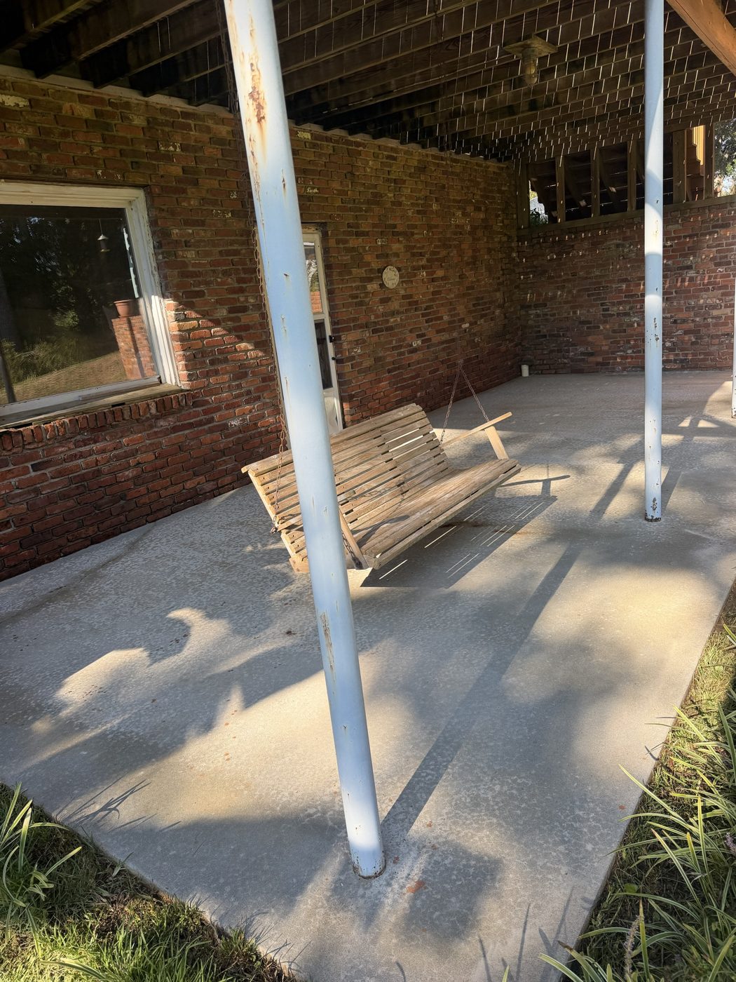 Covered back porch concrete and porch swing after pressure washing, clean and bright