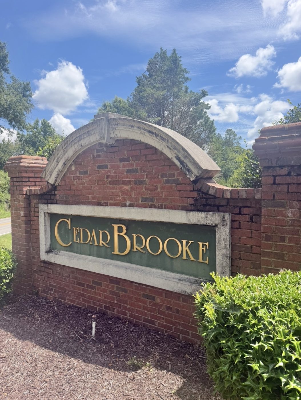 Cedar Brooke entrance sign from the side before cleaning, dark streaks on the arch